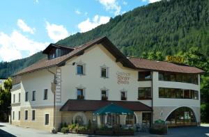 ein großes weißes Gebäude mit einem Berg im Hintergrund in der Unterkunft Gasthof Rieder Stubn in Ried im Oberinntal