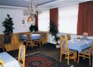 a restaurant with two tables and chairs and a chandelier at Pension Grein in Pfunds