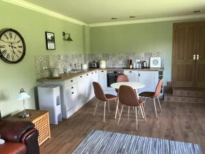 a kitchen with a table and chairs and a clock at One Slade Gardens in The Mumbles