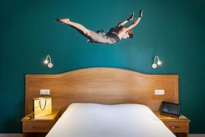 
a person jumping up into the air on top of a bed at The Originals Boutique, Grand Hôtel de la Gare, Toulon in Toulon
