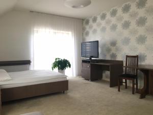 sypialnia z łóżkiem, biurkiem i telewizorem w obiekcie Hotel i Restauracja Jan w Bełchatowie
