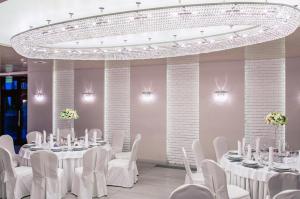 ベウハトゥフにあるHotel i Restauracja Janの白いテーブルと白い椅子、シャンデリアが備わる客室です。