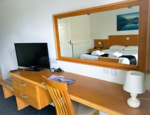 Habitación con escritorio, TV y cama. en The Beach Motel, en Trearddur
