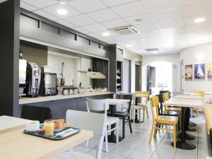 un restaurante con mesas y sillas y una cocina en B&B HOTEL Hyeres en Hyères