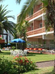 um hotel com mesas e cadeiras e um guarda-sol em Hotel Marina em Marina di Massa