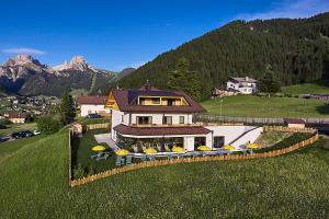 uma casa grande numa colina com um campo verde em Residence La Selva em Selva di Val Gardena