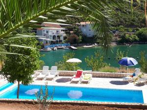 a pool with chairs and umbrellas next to a body of water at Villa Marica in Neum