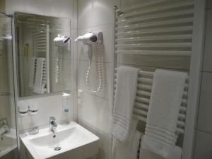 a white bathroom with a sink and a mirror at Hotel Kaiserhof in Siegburg