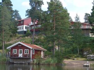a red house on a hill next to a house on a lake at Stiftsgården Vårdnäs Hotell in Brokind