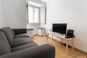 a living room with a couch and a table with a television at Casa Sanches in Cascais