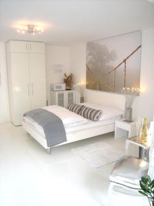 a white bedroom with a bed and a bridge painting on the wall at A-Partments in Cologne