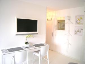 ケルンにあるア パートメンツの白いデスク、壁掛けテレビが備わる客室です。