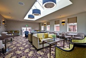 a restaurant with couches and tables and chairs at Pontlands Park Hotel in Chelmsford