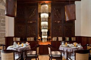 a dining room with two tables and chairs and chandeliers at Villa De L'Ô in Essaouira