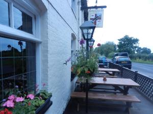 two picnic tables on the side of a building with flowers at The Hawkenbury in Staplehurst
