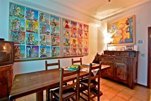 une salle à manger avec une table en bois et un mur orné de peintures dans l'établissement Affittacamere La Casa Di Elide, à Arezzo