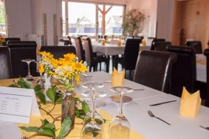 un tavolo con fiori gialli e bicchieri da vino sopra di Gasthaus Pension Goldeck a Spittal an der Drau