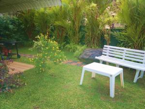 a white bench and a stool in a garden at Kandy Royal Resort in Kandy