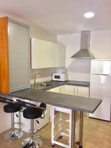 a kitchen with a counter with stools and a sink at Apartamento JALAMA 2B in Moraleja