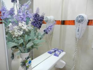 un baño con un jarrón de flores y un espejo en Hotel Colon en Posadas