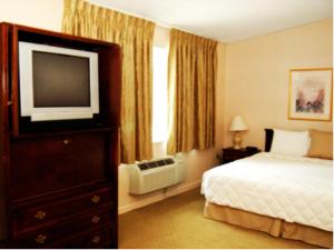 ホープウェル・ジャンクションにあるInn at Arbor Ridge Hotel and Conference Centerのベッド1台、薄型テレビが備わるホテルルームです。