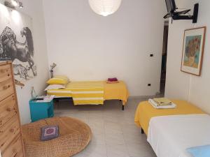 Habitación con 3 camas con sábanas amarillas. en Buonanotte & Buongiorno Guesthouse, en Nápoles