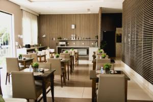 um restaurante com mesas e cadeiras e uma cozinha em Class Hotel Varginha em Varginha
