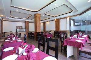 a dining room with tables and chairs with pink tablecloths at Hotel The Royal Krishna in Katra