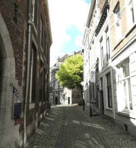 an empty city street with buildings and a tree at Galerie Hotel Dis in Maastricht