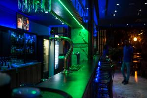Hotel Elegance NV في باراماريبو: بار مع أضواء خضراء وزرقاء على المنضدة