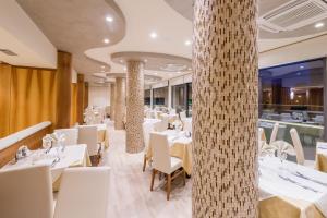 ein Restaurant mit weißen Tischen und weißen Stühlen in der Unterkunft Hotel Mayer in Bibione