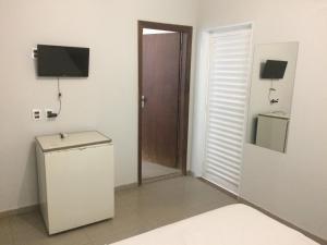 a room with a door and a television on a wall at Roda Viva Park Hotel in Jales