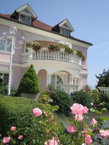 a pink house with a white balcony and pink roses at Villa Rose in Sankt Kanzian