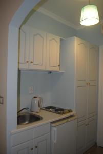 a kitchen with white cabinets and a sink at Apollonia Hotel in Masouri