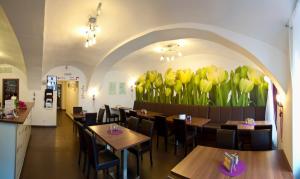 ein Restaurant mit Tischen und gelben Tulpen an der Wand in der Unterkunft Hotel Berger in Kamenice nad Lipou