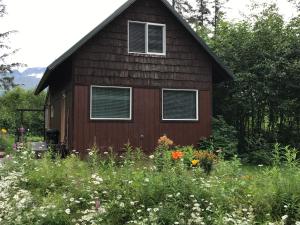 a brown house with windows and a field of flowers at Resurrection River Rentals in Seward