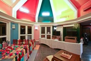 Habitación con techos coloridos, mesas y sillas. en Club Punta Fuego, en Nasugbu