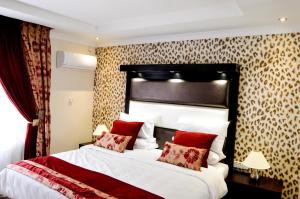 a bedroom with a large bed with red pillows at Golden Door Villa in Gaborone
