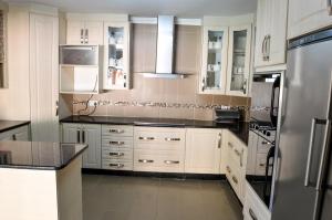 a kitchen with white cabinets and a stainless steel refrigerator at Golden Door Villa in Gaborone