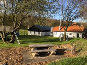 a stone bench in a park with a building at LindegaardApartment - woods and sea in Hejls