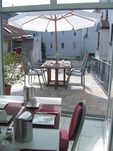 eine Terrasse mit einem Tisch, Stühlen und einem Sonnenschirm in der Unterkunft Zum Löwen in Bad Homburg vor der Höhe