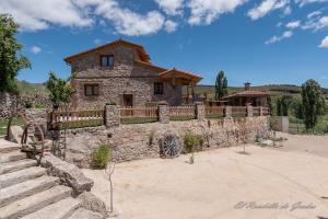 an old stone house with a wooden fence at El Rondillo de Gredos in Hoyos del Collado