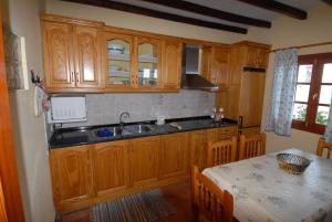 una cocina con armarios de madera y una mesa con mesa. en Casa Rural El Roque en Taibique