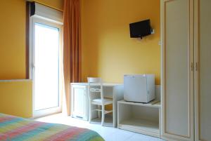 een slaapkamer met een bed, een bureau en een televisie bij Hotel Michelangelo in Teramo