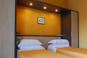 2 letti in una camera con pareti gialle di Hotel Michelangelo a Teramo