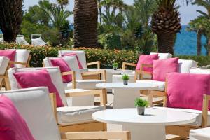 a row of tables and chairs with pink cushions at Sandy Beach Hotel & Spa - ex Sentido in Larnaca