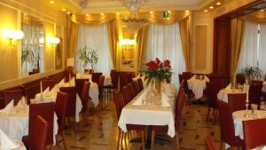 a dining room with white tables and chairs and flowers at Albergo Corona in Domodossola