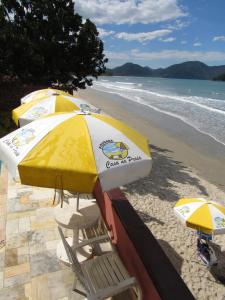 
a beach area with chairs and umbrellas at Pousada Casa na Praia in Ubatuba
