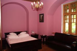 ein Schlafzimmer mit lila Wänden und einem Bett und einem Sofa in der Unterkunft Klasztor Cedynia Hotel in Cedynia