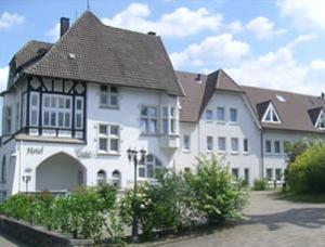 uma grande casa branca com um telhado castanho em Hotel Cordial em Lennestadt